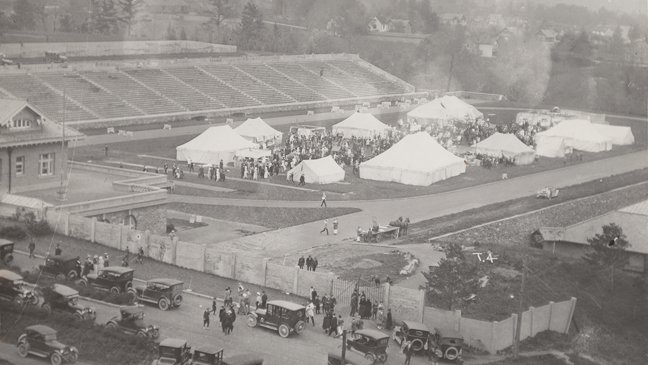 Numerous tents and crowds of people on the football field.